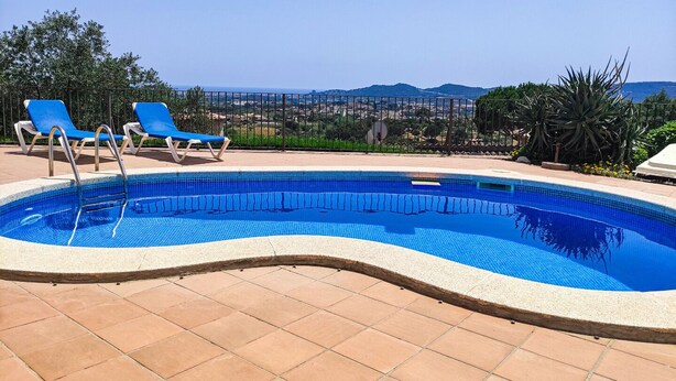 En swimmingpool med blå fliser, omgivet af en fliseterrasse.
