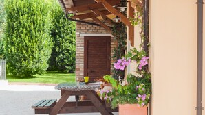 A patio area with a table and chairs, a brick wall, and potted plants. - "Casale Giacinta" ancient cottage between sea and mountains with swimming pool (Pianella (PE))