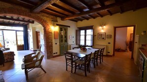 A spacious dining area with a wooden table and chairs, a brick column, and a view of the outside through a large window. - Francesca 3 Extra Suite pool and whirlpool (Camaiore)