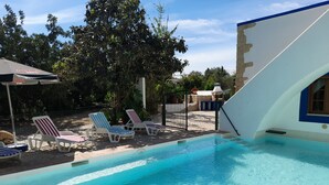 A swimming pool with lounge chairs and a stone wall. - Quinta Do Pomarinho 46328/AL  (Tavira)