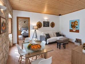 A modern living room with a glass dining table, white chairs, a sofa, and a coffee table. - Quinta Do Pomarinho 46328/AL  (Tavira)