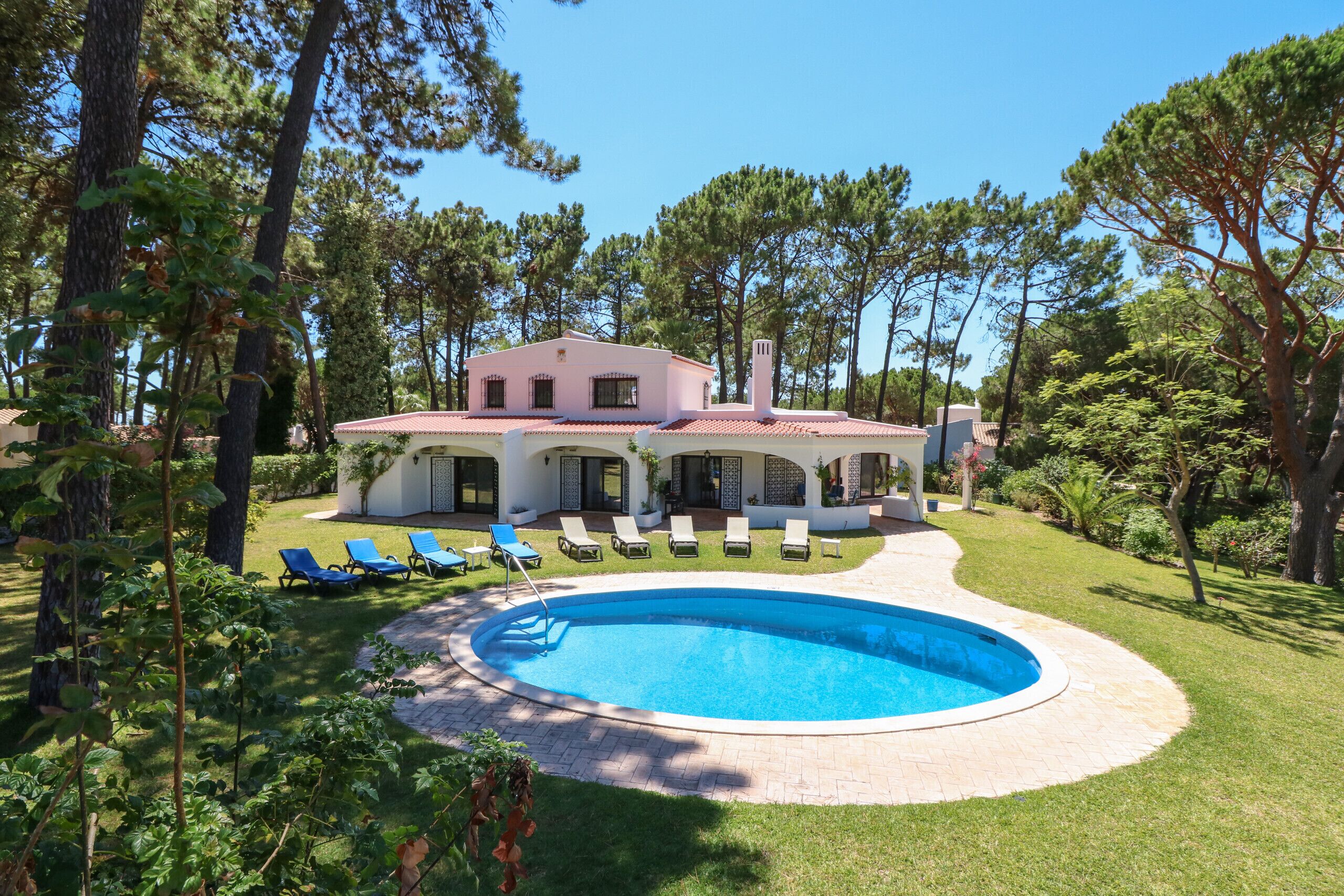 A house with a swimming pool, surrounded by trees and a lawn.