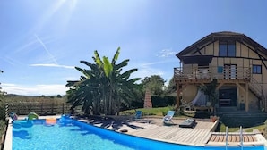 Une grande maison avec une piscine, une terrasse en bois et un jardin.