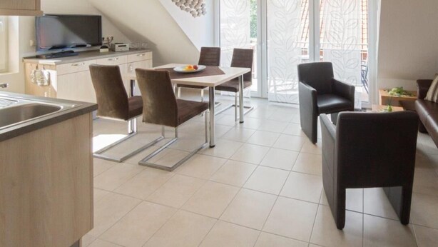 Una cocina moderna con comedor, televisión y balcón con vistas.
