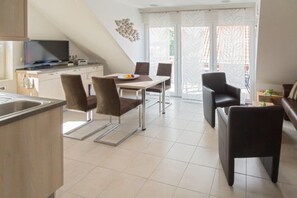 A modern kitchen with a dining area, a television, and a balcony with a view. - Vacation apartment Strandlilie (Norddeich)