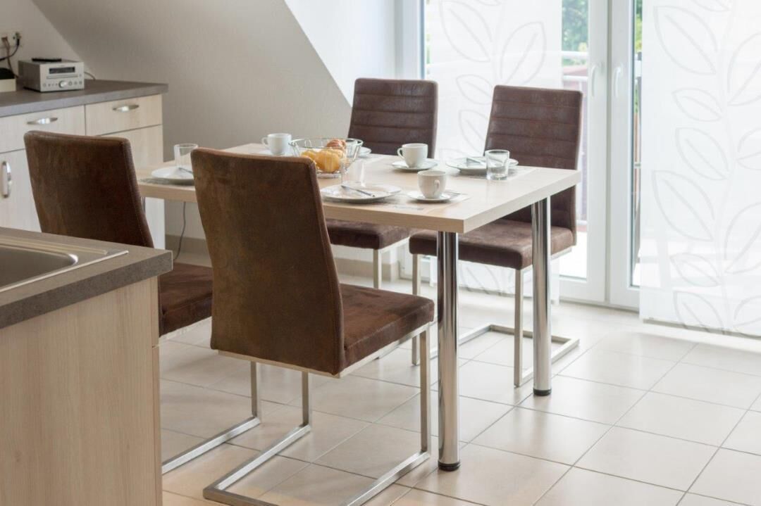 Un coin repas moderne avec une table dressée pour quatre personnes, comprenant des assiettes, des tasses et un saladier en verre.