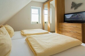 Une chambre avec deux lits, une télévision et une armoire.