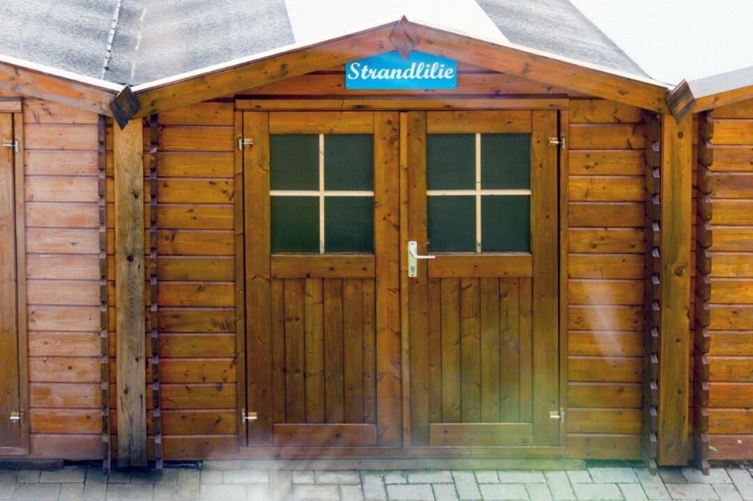 Una cabaña de madera con un letrero que dice "Strandlilie" sobre la entrada.
