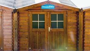 Una cabaña de madera con un letrero que dice "Strandlilie" sobre la entrada.