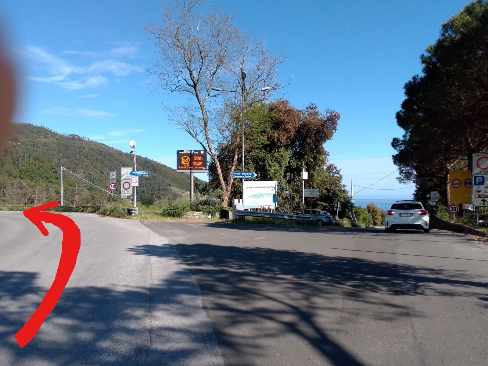 Una carretera con señales de tráfico, un cartel de límite de velocidad y un automóvil.
