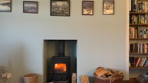 Una habitación con chimenea, estanterías y cuadros en la pared.