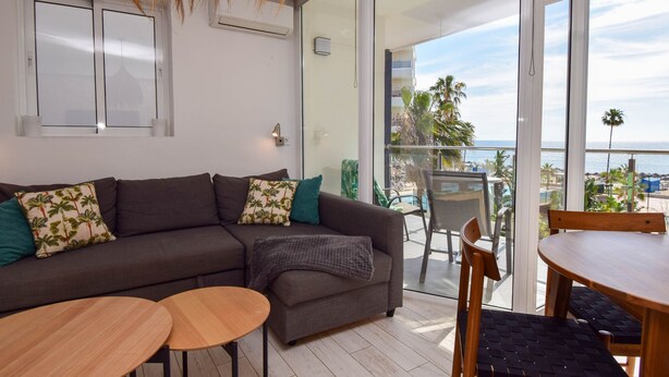 A modern living room with a sofa, two side tables, and a balcony with a view of the sea. - Ref: 255 Fully renovated 1-bedroom apartment with sea views in the heart of Los Boliches, Fuengirola, ideally located just one row back from the beach (Fuengirola)