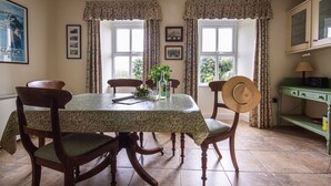 A dining area with a table set for four, surrounded by patterned curtains and framed pictures on the walls.