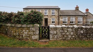 A stone house with a traditional design, featuring a stone wall and a gated entrance.