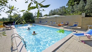 A swimming pool with clear blue water, surrounded by lounge chairs and umbrellas. - Studio with private balcony, great views, wifi, shared pool, close to village (Vinci, Florence)