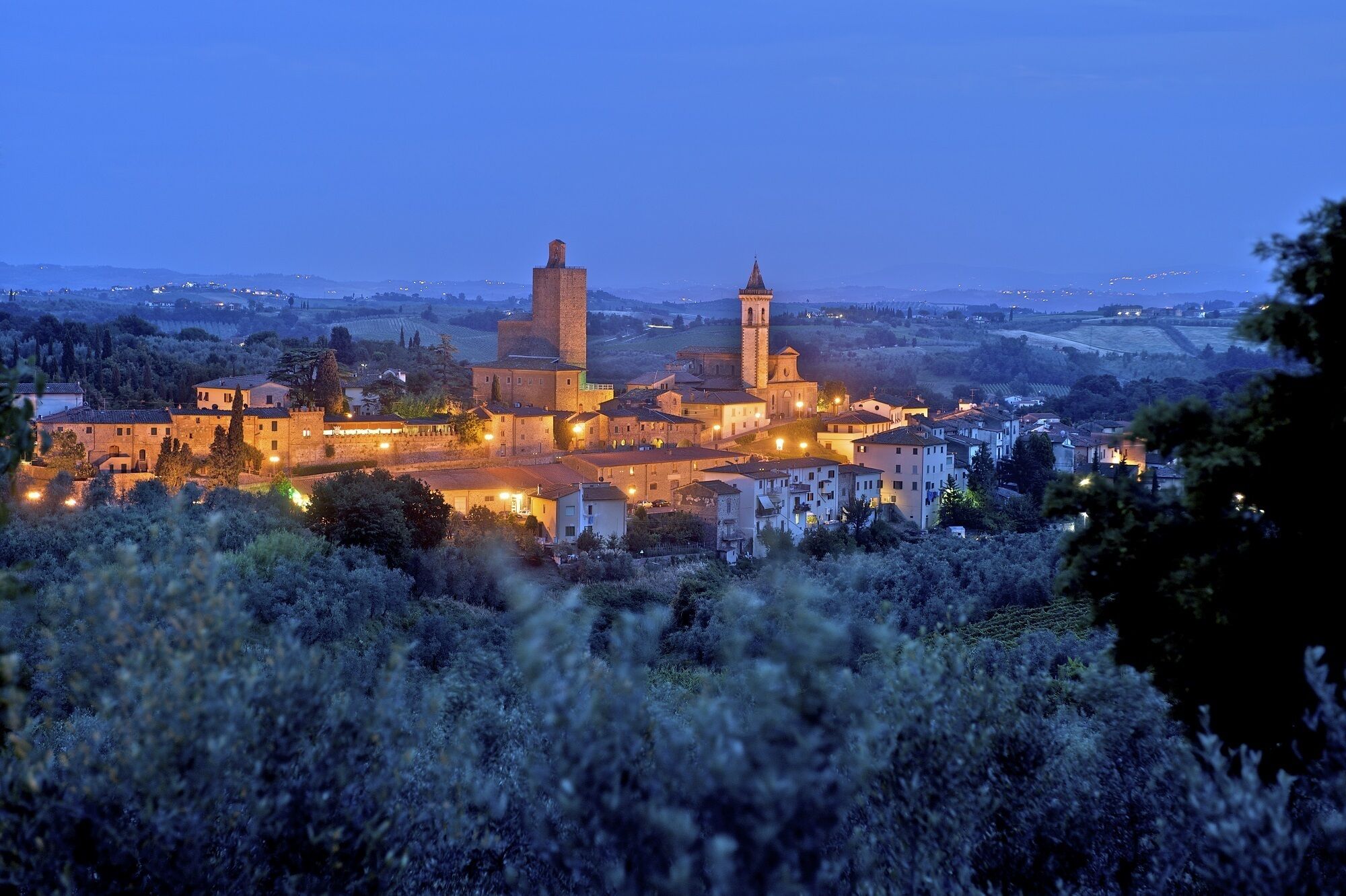 A historic town with medieval architecture, including a prominent tower and a church with a bell tower.