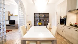 A modern kitchen with a dining area, built-in shelves, and a TV. - Cozy apartment in the historic heart of Piombino (Piombino)