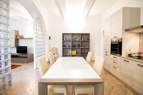 Una cocina moderna con comedor, estanterías integradas y televisor.