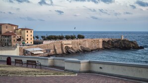A coastal promenade with a stone wall, benches, and a lighthouse in the distance. - Cozy apartment in the historic heart of Piombino (Piombino)