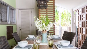Una mesa de comedor con cuencos blancos, copas de vino y un jarrón con flores blancas.