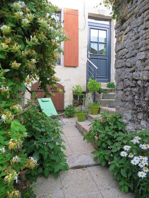 Stroll through this charming courtyard, surrounded by lush plants and a traditional stone wall.