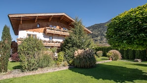 Eine traditionelle Chalet mit Holzbalkon, umgeben von gepflegten Gärten und einer Bergkulisse.