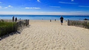 Ein Sandstrand mit einer Holzzahlung, blauem Himmel und ruhiger See.