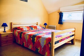 Een slaapkamer met een houten bed, twee bedlampen, een radiator en een raam met gordijnen.