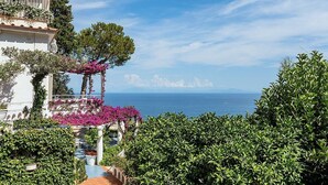 Une propriété située sur la côte, dotée d’une terrasse avec vue sur la mer, d’une végétation luxuriante et d’un ciel dégagé.