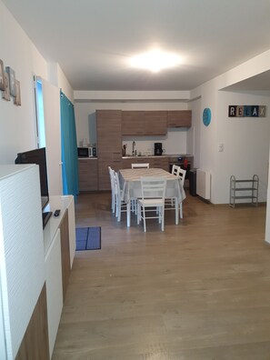 A modern kitchen with wooden cabinets, a dining table with chairs, and a kitchen island.