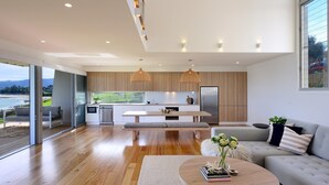 Een moderne keuken met houten kastjes, een ingebouwde oven en een koelkast. Er is een zithoek met een bank en een bijzettafeltje.