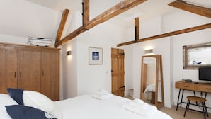 Ein Schlafzimmer mit Bett, Holzschrank, Schreibtisch und Spiegel.