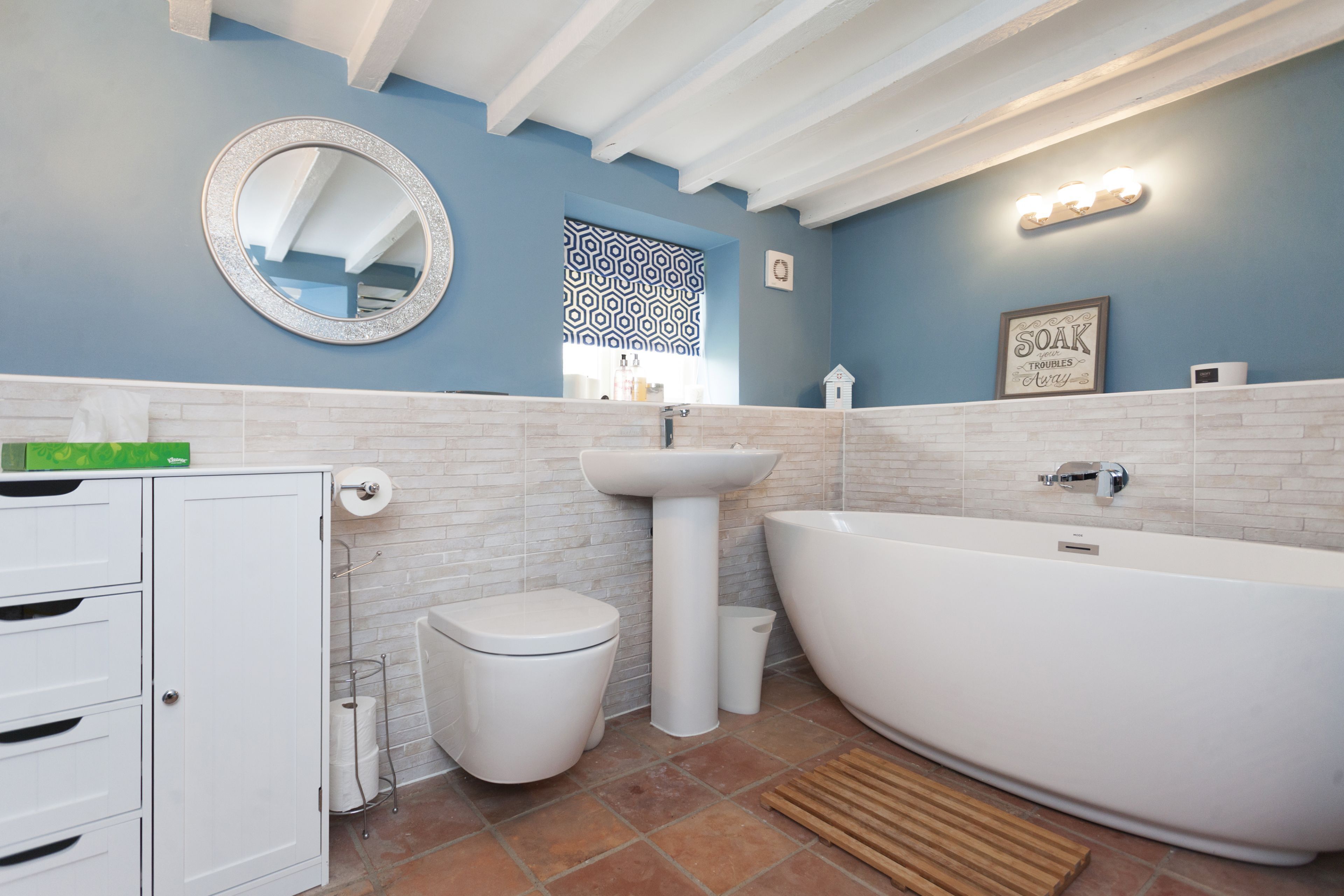 Ein Badezimmer mit einer weißen Badewanne, einem Waschbecken, einer Toilette und einem Spiegel.