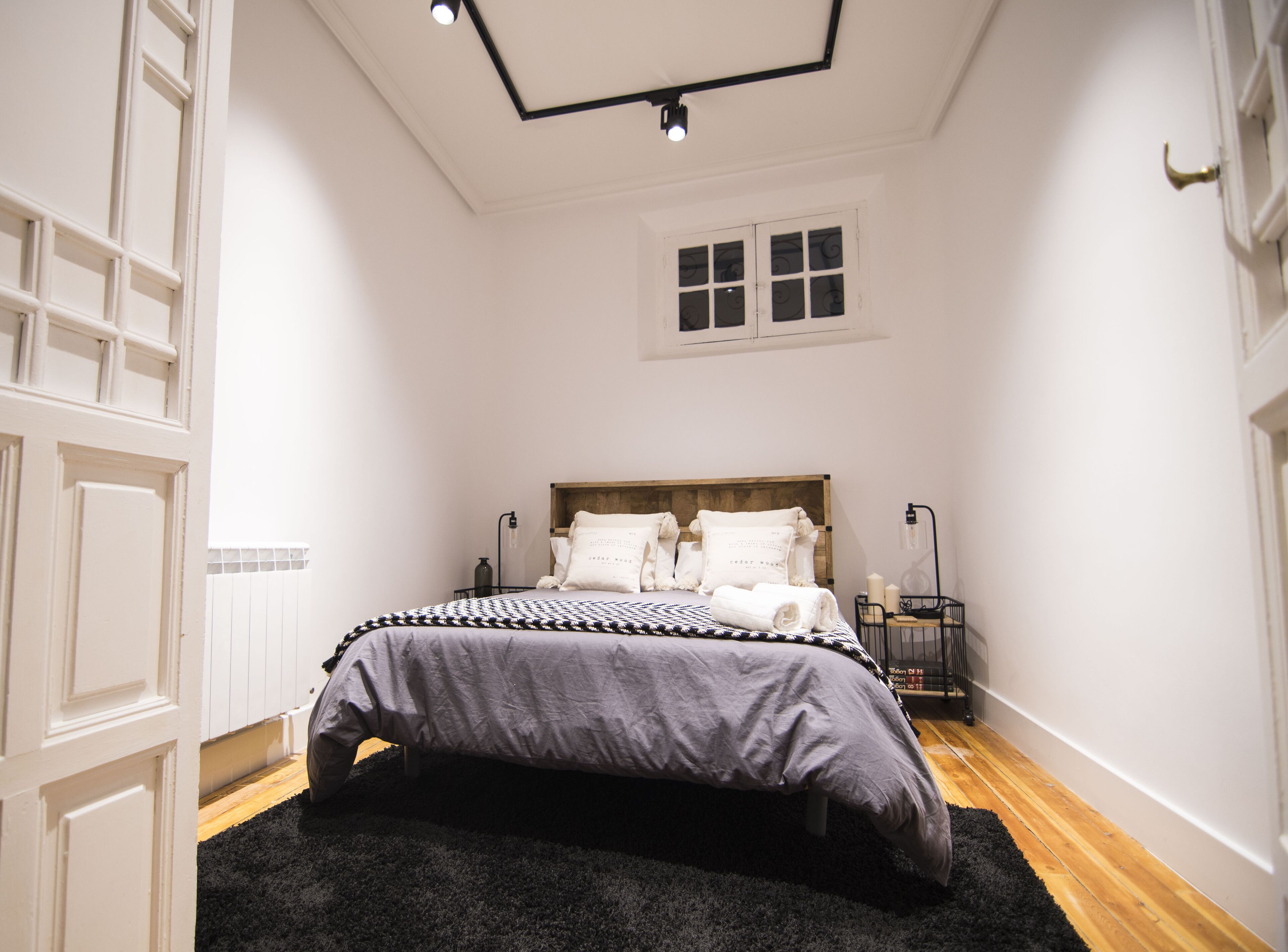 Une chambre à coucher avec un lit, une table de chevet, une lampe et une fenêtre.