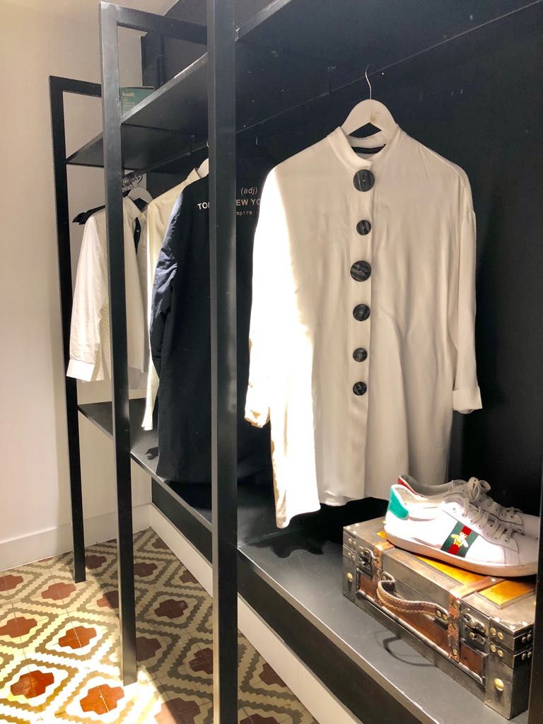 En klädställning med olika plagg, ett par sneakers och en resväska.