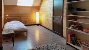 A cozy room with a bed, a desk, a shelf with toys, and a door.