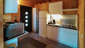 A compact kitchen with wooden walls, a built-in stove, and white cabinets.