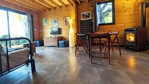 A cozy cabin interior with a bed, a table, chairs, a fireplace, and a television.