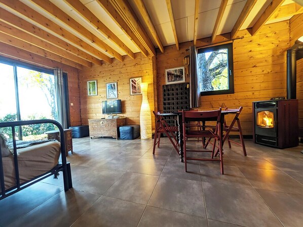 L’intérieur d’un chalet confortable, avec un lit, une table, des chaises, une cheminée et un téléviseur.