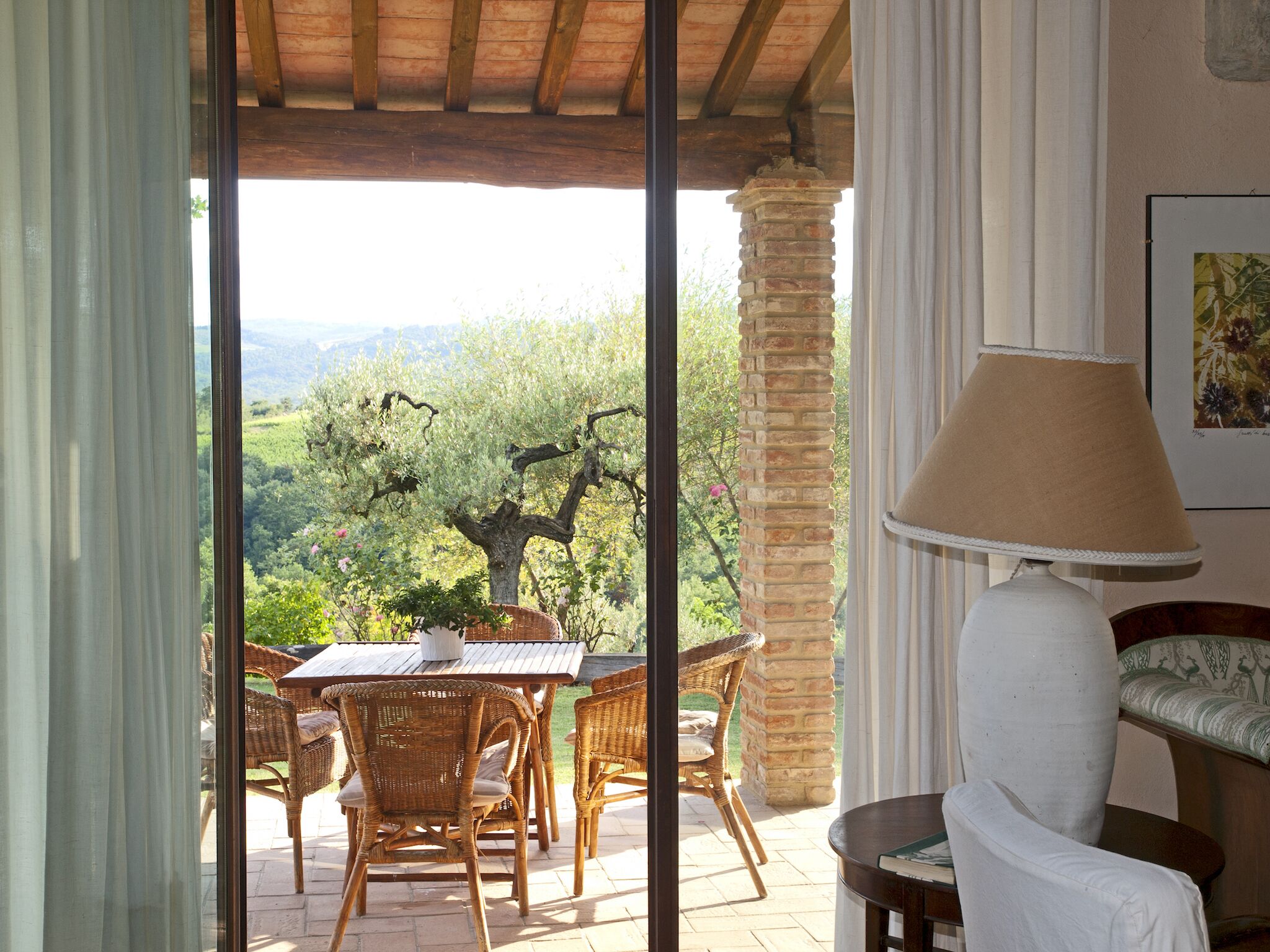 A patio with wicker furniture, a table, and a lamp.