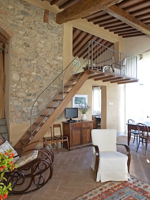 A spacious living area with a stone wall, wooden staircase, and a dining area with chairs and a table. - Country House Nazzano in Vineyards/Olive Grove near San Gimignano Florence Siena (Gambassi Terme)