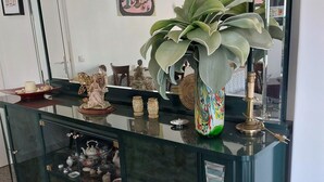A modern interior with a glass-top dining table, a decorative plant, and a statue.