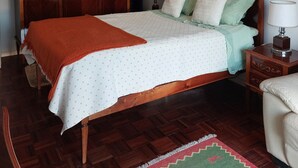 A bedroom with a wooden bed, a nightstand, a wardrobe, and a ceiling light.