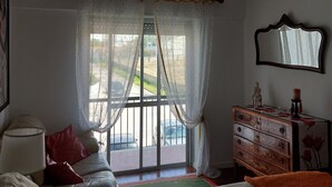 A bedroom with a bed, a dresser, a mirror, and a window with curtains.