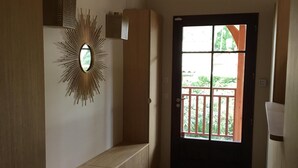 A hallway with a wooden bench, a decorative mirror, and a door leading to an outdoor balcony.