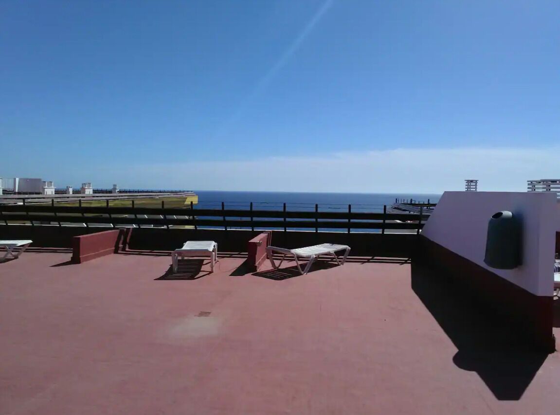 Een terras op het dak met lounge stoelen en uitzicht op de oceaan.