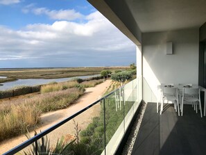 A balcony with a view of a coastal landscape, including a sandy path and water bodies.