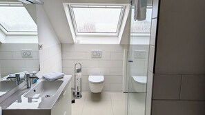 A modern bathroom with a skylight, a bathtub, a toilet, and a shower area. - Modern apartment for 5 people near the pier (Lüdinghausen)