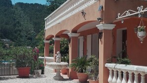 A building with a tiled patio, potted plants, and a statue.