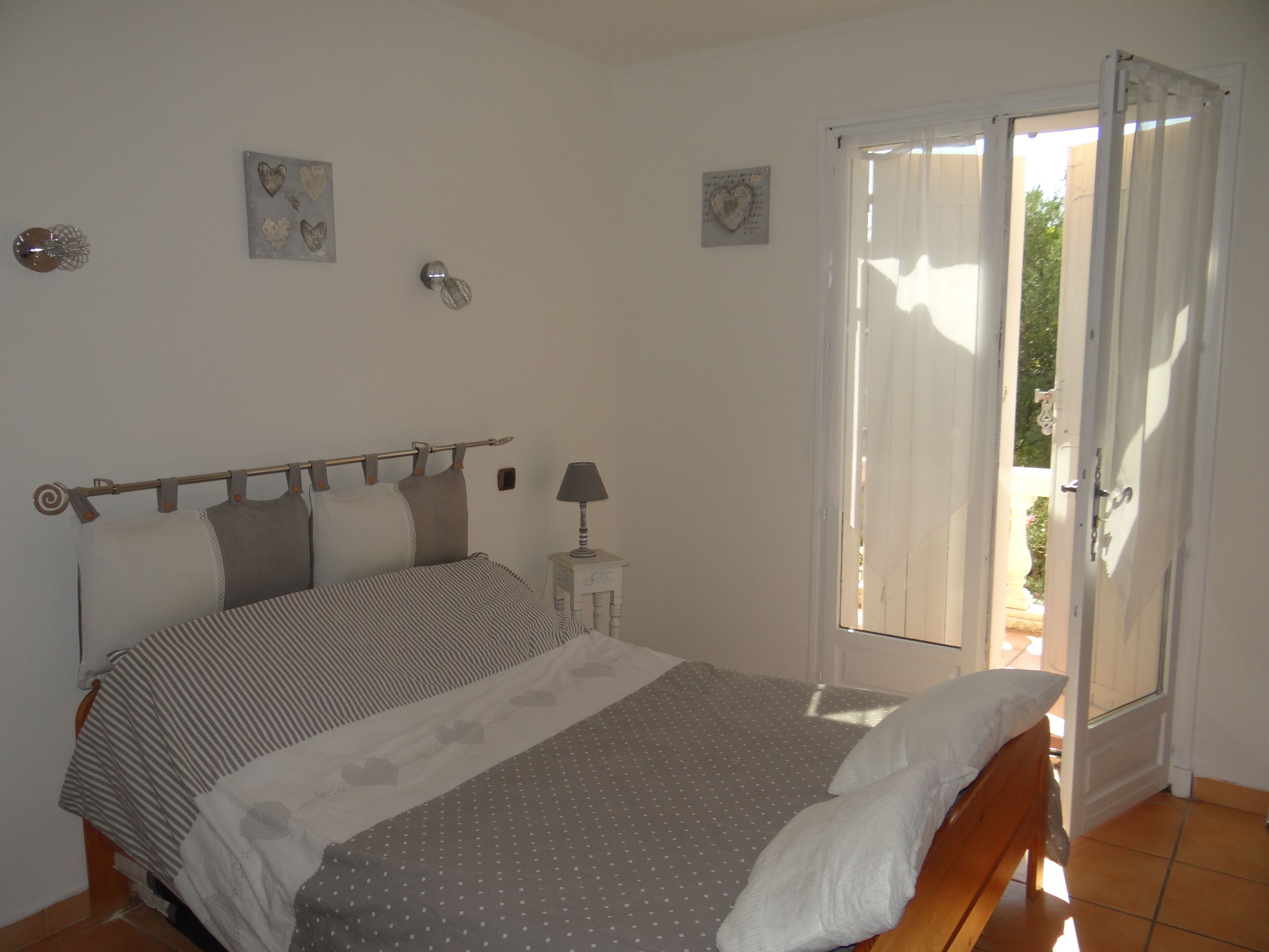 A bedroom with a bed, a nightstand, a window with curtains, and wall decorations.